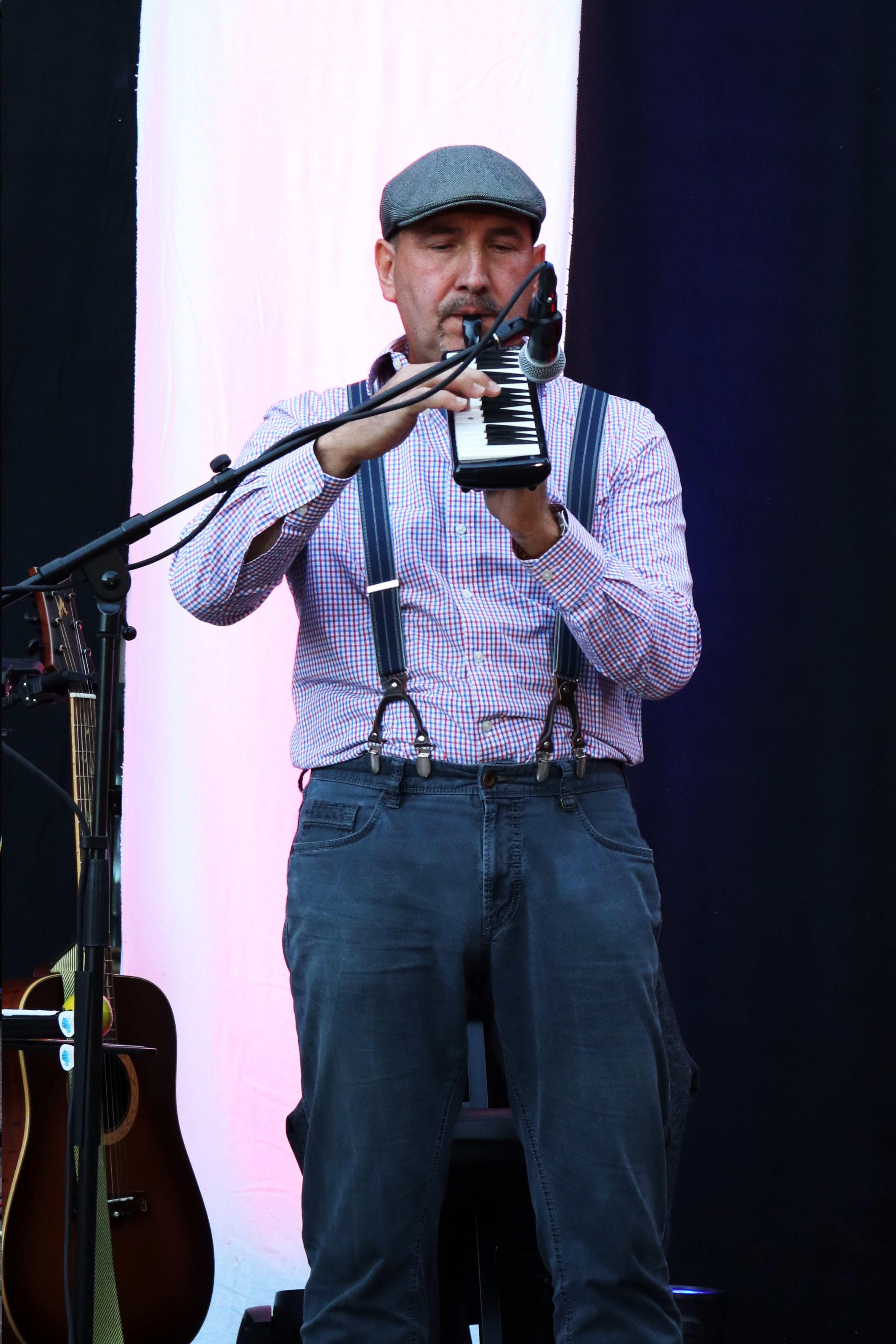 Auf dem Bild sieht man Henrik, wie er Melodica spielt. Im Hintergrund ist eine Gitarre zu sehen.